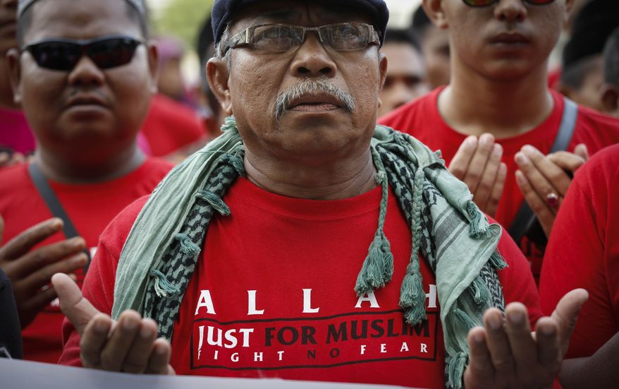 ** FILE ** Muslim demonstrators pray outside the Court of Appeal in Putrajaya, outside Kuala Lumpur, Malaysia, Monday, Oct. 14, 2013. A Malaysian appeals court on Monday upheld a government ban against the use of the word "Allah" to refer to God in non-Muslim faiths, overruling claims by Christians in this Muslim-majority nation that the restriction violates their religious rights. "Allah" is the Arabic word for God and is commonly used in the Malay language to refer to God. (AP Photo/Vincent Thian)