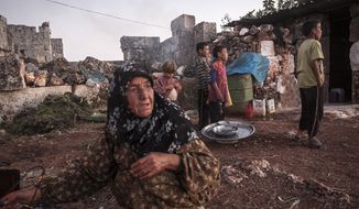 A displaced Syrian woman cooks a meal as children play in the sunset near Kafer Rouma in ancient ruins used as temporary shelter by families who have fled the heavy fighting and shelling in the Idlib provincial countryside of Syria. (AP Photo/Narciso Contreras)