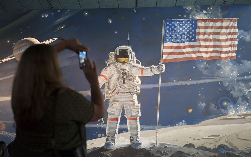 A woman takes a photograph of a mural at the Smithsonian's Air and Space Museum in Washington, Thursday, Oct. 17, 2013. Barriers went down at federal memorials, National Park Service sites, as well as the Smithsonian Institution's network of popular museums and thousands of furloughed federal workers returned to work across the country Thursday after 16 days off the job due to the partial government shutdown. (AP Photo/Cliff Owen)