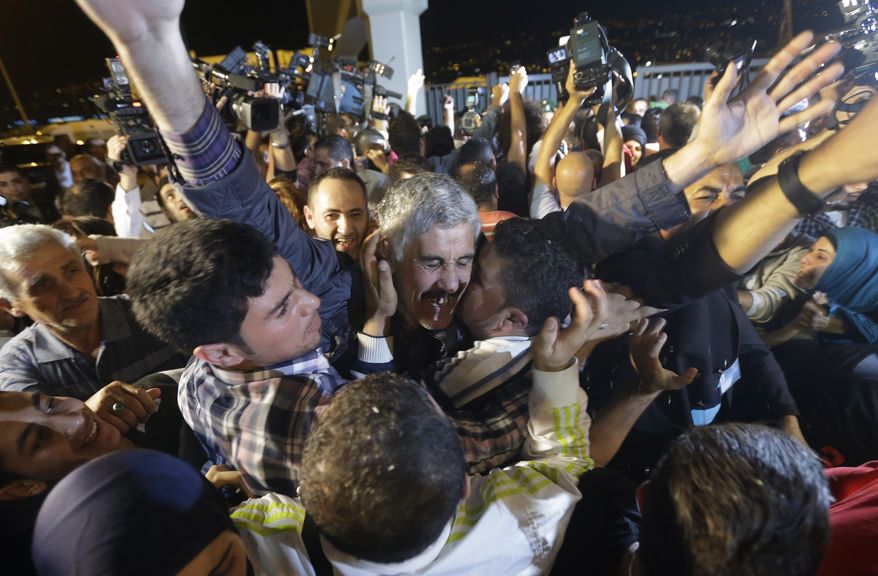 Abbas Hammoud, one of the nine Lebanese Shiite pilgrims who were kidnapped by a rebel faction in northern Syria in May 2012, is embraced by his relatives upon his arrival at Rafik Hariri International Airport in Beirut on Saturday, Oct. 19, 2013. His release was part of an ambitious three-way deal cutting across the Syrian civil war. (AP Photo/Hussein Malla)