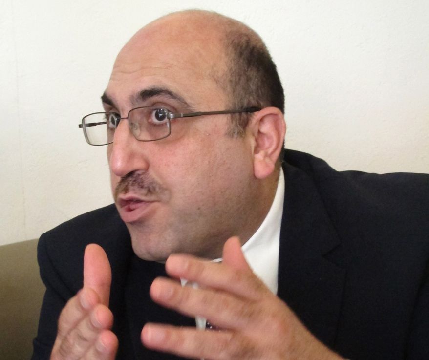 Rami Abdurrahman, head of the Britain-based Syrian Observatory for Human Rights, gestures during an interview with The Associated Press in Coventry, England, on Wednesday, Oct. 10, 2013. (AP Photo/Raphael Satter)