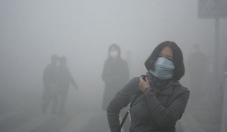A woman wearing a mask walk through a street covered by dense smog in Harbin, northern China, Monday, Oct. 21, 2013. Visibility shrank to less than half a football field and small-particle pollution soared to a record 40 times higher than an international safety standard in one northern Chinese city as the region entered its high-smog season. (AP Photo/Kyodo News) JAPAN OUT, CREDIT MANDATORY