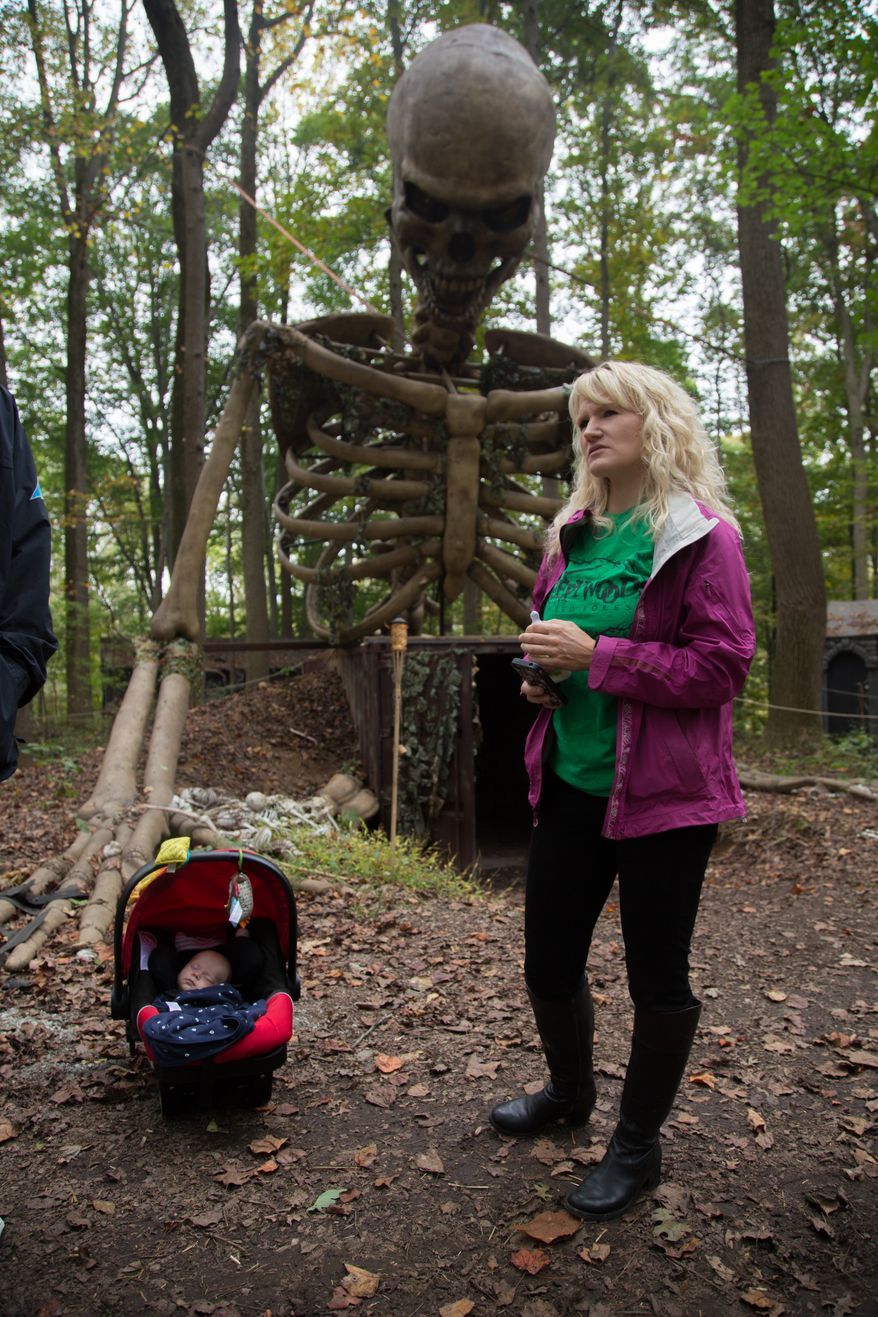 Jill Bennett, owner of the Creepy Woods Haunted Woods and Bennett's Curse Haunted Houses, stands under a 35 foot tall animatronic skeleton that they just installed this year, with her Son, Allen Jr. fast asleep, in Kingsville, MD., Wednesday, October 16, 2013. (Andrew S Geraci/The Washington Times)