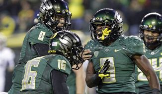 Oregon running back Byron Marshall, right, celebrates his touchdown with teammates Daryle Hawkins (16) and quarterback Marcus Mariota (8) during the second half of an NCAA college football game against UCLA in Eugene, Ore., Saturday, Oct. 26, 2013. Marshall ran for 133 yards and three touchdowns for a 42-14 victory. (AP Photo/Don Ryan)