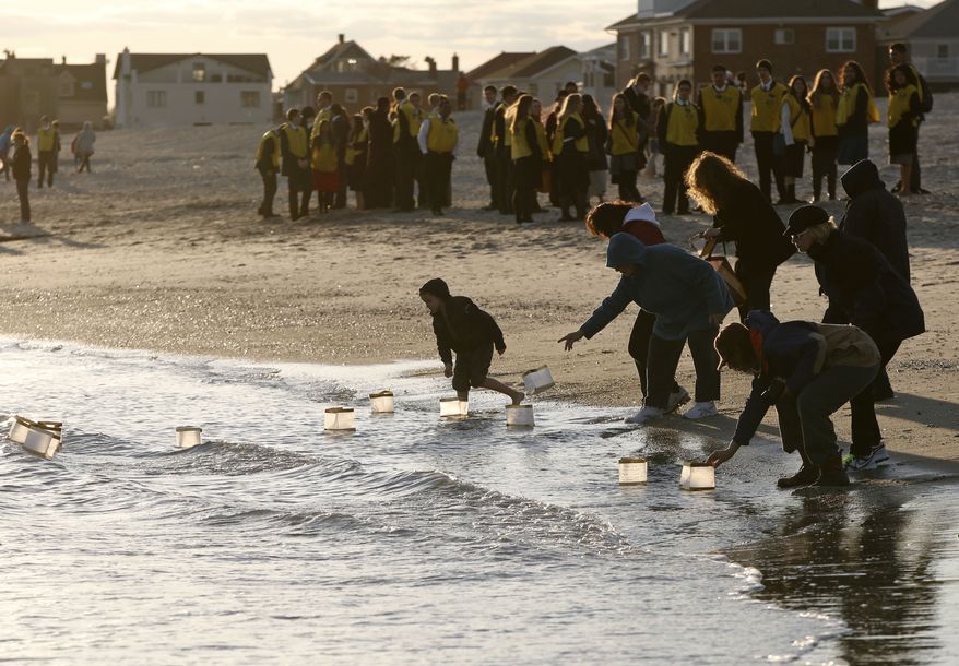 Rockways residents float lanterns containing handwritten personal messages in the water at the conclusion of "Rockaways Rising: Hands Scross the Sand," commemorating the one year anniversary of Superstorm Sandy, Sunday, Oct. 27, 2013, in New York. The actual one year anniversary of Superstorm Sandy is Tuesday, Oct. 29. (AP Photo/Kathy Willens)