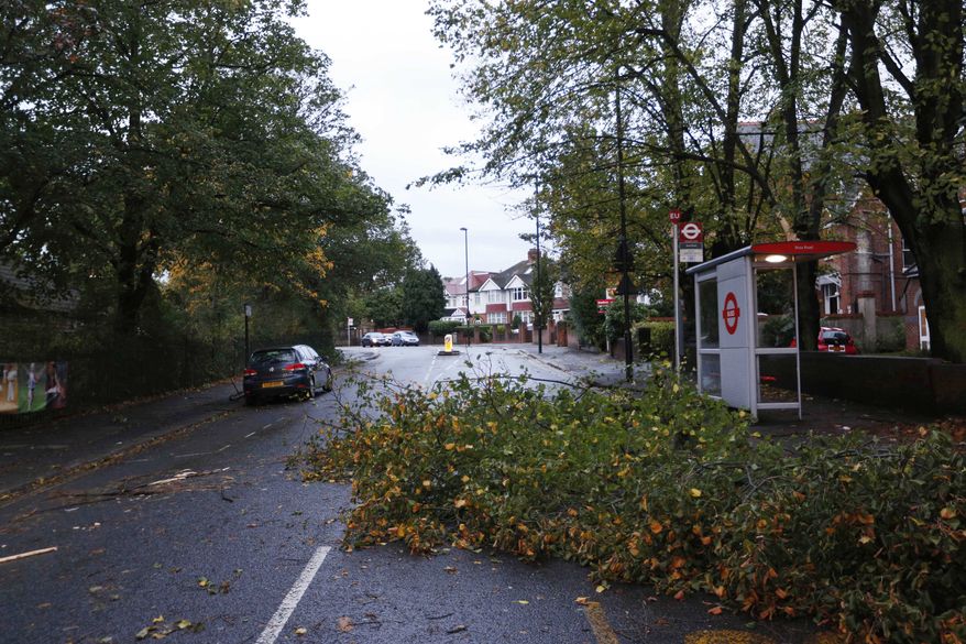 A fallen tree branch partially blocks a road in London, Monday, Oct. 28, 2013. A major storm with hurricane-force winds is lashing southern Britain, causing flooding and travel delays including the cancellation of roughly 130 flights at London's Heathrow Airport. Some rail lines shut down Monday morning, and some roads were closed due to fallen trees and power lines. Air travelers and commuters were advised to check conditions before starting any journeys. Widespread delays were expected as major London train lines delayed their opening because of the winds and tree hazards. (AP Photo/Lefteris Pitarakis)