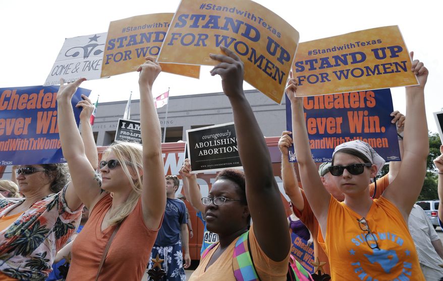File - In this July 9, 2013 file photo, opponents and supporters of an abortion bill hold signs near a news conference outside the Texas Capitol, in Austin, Texas. New abortion restrictions passed by the Texas Legislature are unconstitutional and will not take effect as scheduled on Tuesday, a federal judge has ruled. (AP Photo/Eric Gay, File)