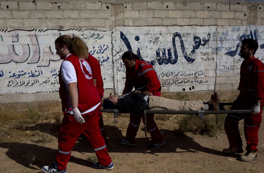 A man is helped by Red Crescent workers on his way from the rebel held suburb of Moadamiyeh to the government held territory Tuesday Oct. 29, 2013 in Damascus, Syria. Nearly 2,000 residents of the besieged western Damascus suburb of Moadamiyeh have fled their homes and have surrendered to the Syrian authorities after reports of starvation and disease triggered an international outcry for their help. (AP Photo/Dusan Vranic)