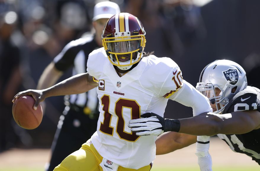 FILE - In this Sept. 29, 2013 file photo, Washington Redskins quarterback Robert Griffin III (10) runs from Oakland Raiders defensive end Jack Crawford (91) during the second quarter of an NFL football game in Oakland, Calif. It used to be the domain of soccer players, NBA forwards and the occasional punter. Now, NFL quarterbacks are getting into the act. They are sports' newest floppers, putting their own tightly spiraled spin on the art of hamming it up to draw the ref's attention and a possible 15-yard penalty. (AP Photo/Ben Margot, File)