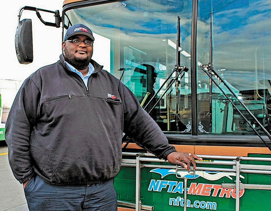 Darnell Barton, a driver for the Niagara Frontier Transportation Authority, poses in front of a bus in Buffalo, N.Y., on Monday, Oct. 28, 2013. On Oct. 18, Mr. Barton's decisive action stopped a woman from leaping from a roadway bridge to her death on a highway below. Caught between the rules of his job and his training as a first responder, Mr. Barton stopped his bus, grabbed the woman and brought her back over the rail to safety. (AP Photo/Niagara Frontier Transportation Authority, Doug Hartmayer)