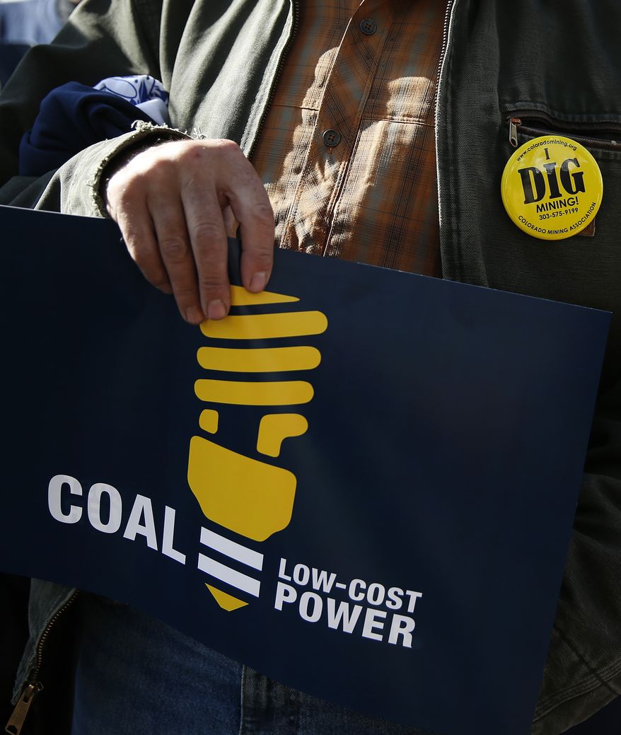 A protester carries a sign and wears a pin during a pro-coal rally in front of the state Capitol, in Denver, Wednesday Oct. 30, 2013. Various industry groups came together for the protest Wednesday, while nearby the Environmental Protection Agency held hearings on future rules to stem emissions from existing power plants, in one of 11 meetings being held across the country. (AP Photo/Brennan Linsley)