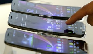 A visitor touches LG Electronics&#39; G Flex smartphone, on display during a media event at the company&#39;s head offices in Seoul on Tuesday, Nov. 5, 2013. The G Flex, which features a curved display and battery, will go on sale Tuesday in the domestic market. (AP Photo/Lee Jin-man)