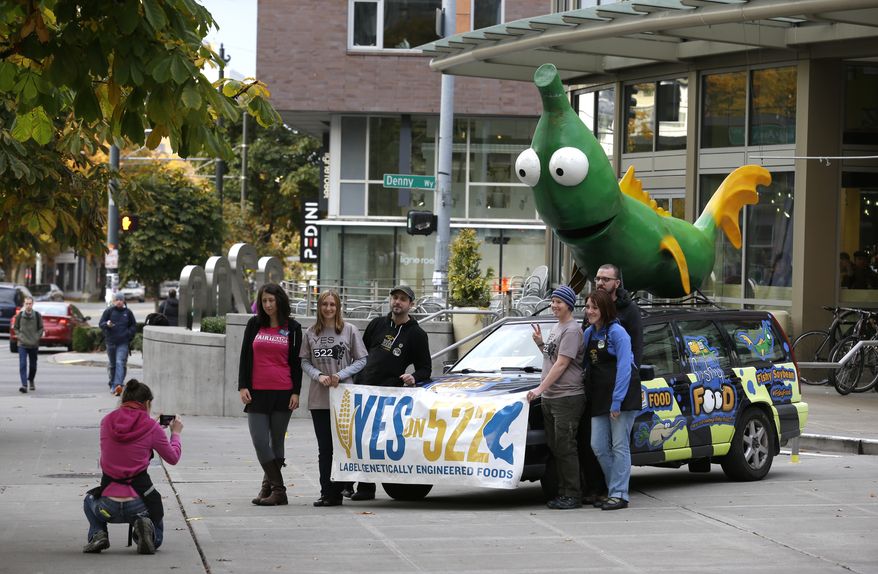 Supporters of Initiative 522 pose for a photo in front of a car with a figurine of a soybean crossed with a fish on it in front of a Whole Foods Market in downtown Seattle, on Election Day, Tuesday, Nov. 5, 2013. The vehicle was promoting a Yes vote on Initiative 522, which would require the labeling of food that contains genetically modified ingredients. I-522 supporters say consumers have the right to know what's in the food they buy, while opponents say the measure would lead to higher food costs. (AP Photo/Ted S. Warren)