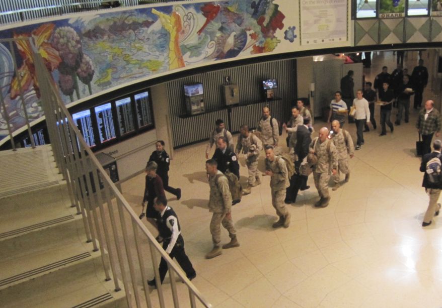 ** FILE ** A group of Marines returning from Afghanistan is escorted through a terminal at Chicago's O'Hare International Airport on Monday, Oct. 4, 2013. The Marines were treated like heroes at the airport, where they received a "water salute" from the airport fire department; cheers from USO volunteers, firefighters, police officers and other airport workers; and first-class seats for the last leg of their journey. (AP Photo/American Airlines, Vic Ysais)