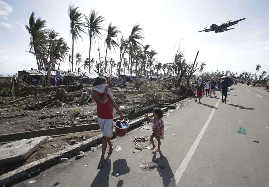 Survivors look up at a military C-130 plane as it arrives at typhoon-ravaged Tacloban city, Leyte province in central Philippines on Monday, Nov. 11, 2013. Stunned survivors of one of the most powerful typhoons ever to make landfall picked through the remains of their homes Monday and pleaded for food and medicine as the Philippines struggled to deal with what is likely its deadliest natural disaster. (AP Photo/Aaron Favila)