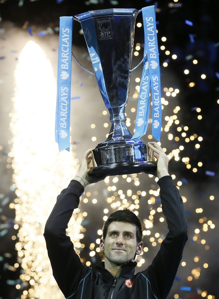 Novak Djokovic of Serbia holds up the ATP World Tour Finals tennis trophy as he poses for photographers after defeating Rafael Nadal of Spain at the O2 Arena in London, Monday, Nov. 11, 2013. (AP Photo/Kirsty Wigglesworth)