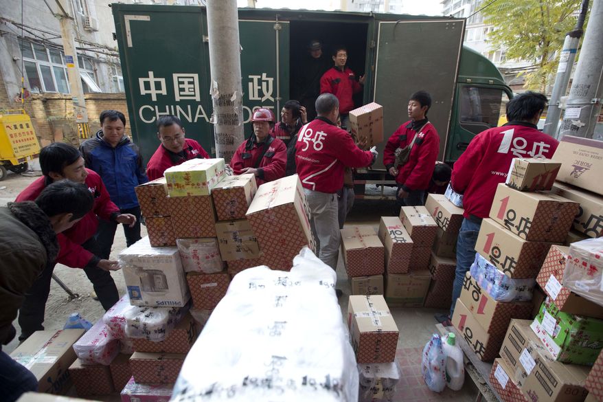 Deliverymen for an online shopping portal sort through goods at a distribution center in Beijing on Monday, Nov. 11, 2013. The date, dubbed "Singles' Day" because unattached young people go on a gift-giving binge to woo each other, has evolved into China's, and possibly the world's, busiest online shopping day. (AP Photo/Ng Han Guan)