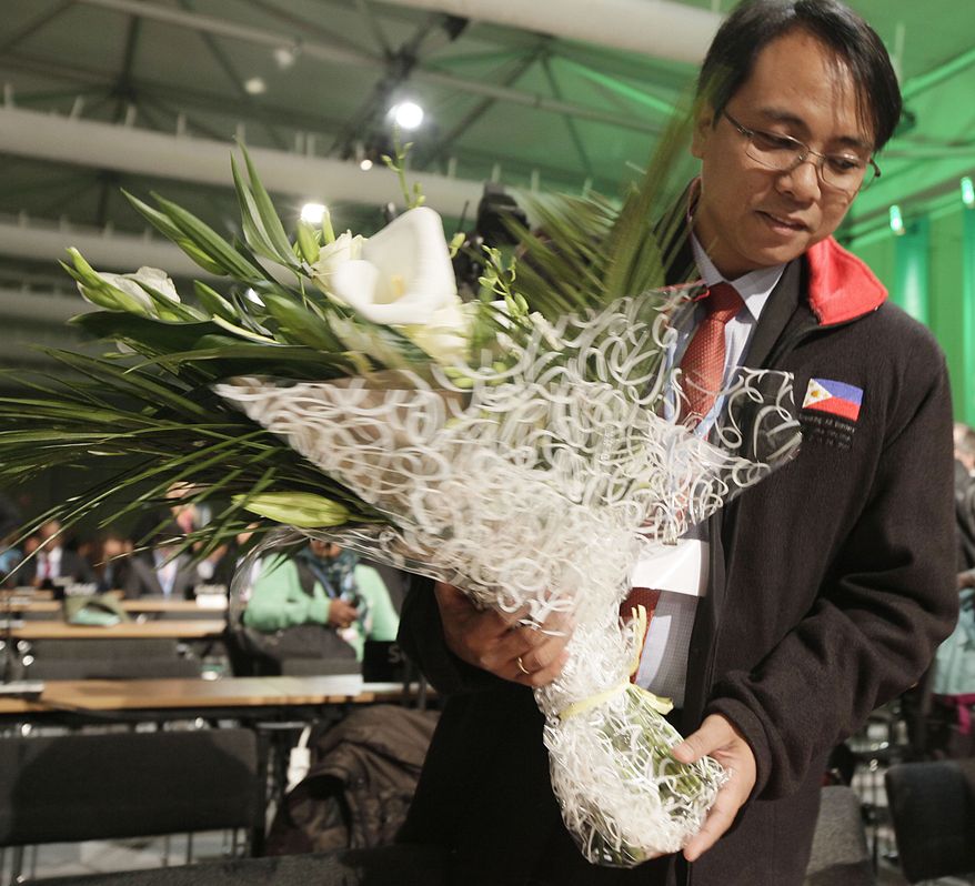 Naderev Sano from the Philippine holds flowers that where presented by other nations and organizations as a sympathy symbol for the Philippine people hit by Typhoon Haiyan during the United Nations Climate Change Conference in Warsaw, Poland, Monday, Nov. 11, 2013. (AP Photo/Czarek Sokolowski)