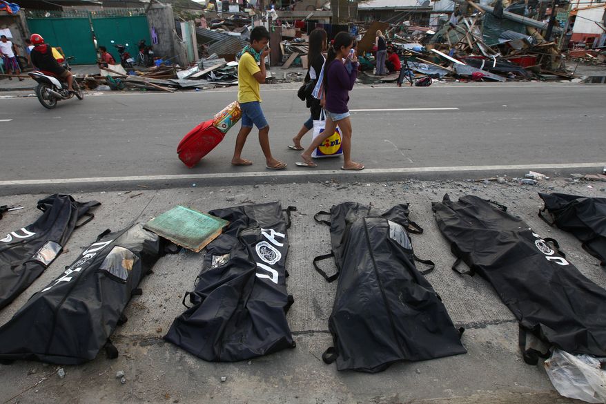People cover their noses from the stench of dead bodies in an area affected by Typhoon Haiyan in Tacloban, Philippines, Wednesday, Nov. 13, 2013. Typhoon Haiyan, one of the strongest storms on record, slammed into six central Philippine islands on Friday, leaving a wide swath of destruction and thousands of people dead. (AP Photo/Dita Alangkara)