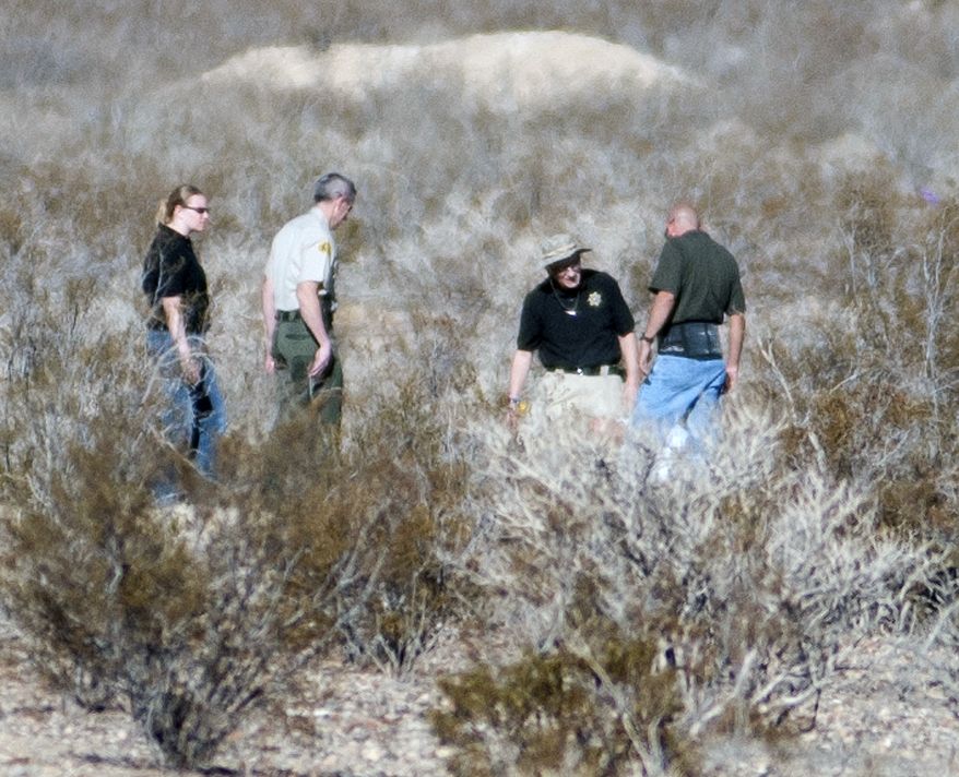 Forensic anthropologists and San Bernardino County Sheriff Department officials investigate two shallow graves where human remains were found in a remote area of Southern California's Mojave Desert in Victorville, Calif., on Wednesday, Nov. 13, 2013. Deputies and coroner's investigators digging through the graves found the remains of four people whose identities remain a mystery. (AP Photo/The Victor Valley Daily Press, Sarah Alvarado)