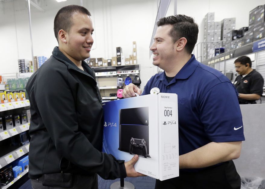 Andy Varadez, left, from Chicago, purchases a Sony PlayStation 4 from Best Buy sales manager Michael Centeno at Lincoln Park Best Buy store in Chicago on Friday, Nov. 15, 2013. The PlayStation 4, which launched Friday, and the Xbox One, which goes on sale next week, face a much-changed gaming and entertainment landscape than their predecessors. (AP Photo/Nam Y. Huh)
