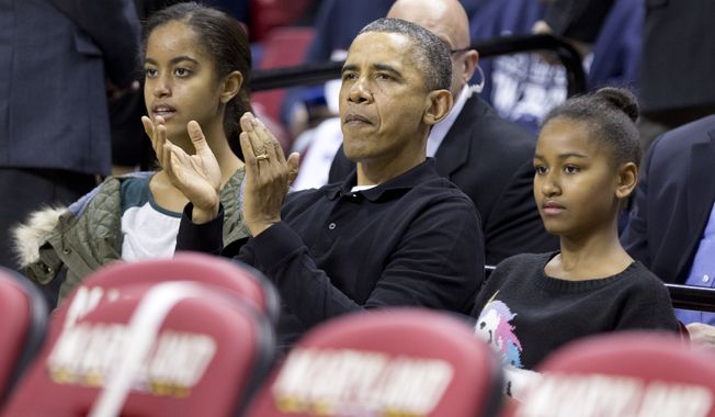 President Barack Obama, center, with his daughters Malia, left, and Sasha, right, cheers as they watch a basketball game between his  brother-in-law Oregon State Beavers Coach Craig Robinson&amp;#8217;s team play against the Maryland Terrapins, Sunday, Nov. 17, 2013, at the Comcast Center in College Park, Md. (AP Photo/Manuel Balce Ceneta) 