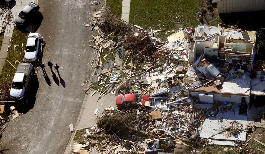 In this aerial photo taken Monday, Nov. 18, 2013, three people walk down a street where homes were destroyed by a tornado that hit the western Illinois town of Washington on Sunday. It was one of the worst-hit areas after intense storms and tornadoes swept through Illinois. The National Weather Service says the tornado that hit Washington had a preliminary rating of EF-4, meaning wind speeds of 170 mph to 190 mph. (AP Photo/Charles Rex Arbogast)