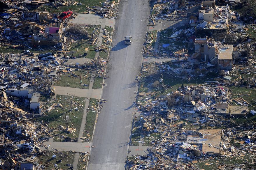 This aerial view on Monday, Nov. 18, 2013, a car drives through a neighborhood that was destroyed by a tornado, in the western Illinois town of Washington on Sunday. It was one of the worst-hit areas after intense storms and tornadoes swept through Illinois. The National Weather Service says the tornado that hit Washington had a preliminary rating of EF-4, meaning wind speeds of 170 mph to 190 mph. (AP Photo/Journal Star, Fred Zwicky)