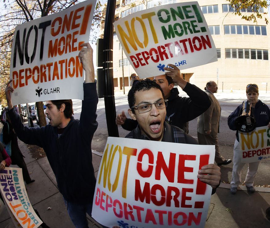 Immigration activists hold signs and shout during a protest in front of a building that houses federal immigration offices Tuesday, Nov. 19, 2013, in Atlanta. Eight activists, protesting deportations of people who are in the country illegally, were taken into custody by police after they locked arms and some of them chained themselves to the gates outside immigration offices. (AP Photo/John Bazemore)