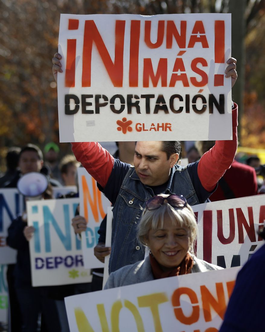 A man marches with a sign during a protest in front of a building that houses federal immigration offices Tuesday, Nov. 19, 2013, in Atlanta. Eight immigration activists, protesting deportations of people who are in the country illegally, were taken into custody by police after they locked arms and some of them chained themselves to the gates outside immigration offices.. (AP Photo/John Bazemore)