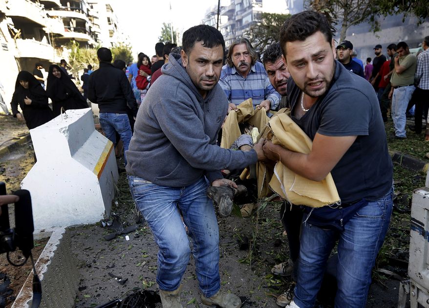 Lebanese citizens carry a dead body, at the scene where two explosions have struck near the Iranian Embassy killing many, in Beirut, Lebanon, Tuesday Nov. 19, 2013. The blasts in south Beirut's neighborhood of Janah also caused extensive damage on the nearby buildings and the Iranian mission. The area is a stronghold of the militant Hezbollah group, which is a main ally of Syrian President Bashar Assad in the civil war next door. It's not clear if the blasts are related to Syria's civil war. (AP Photo/Hussein Malla)