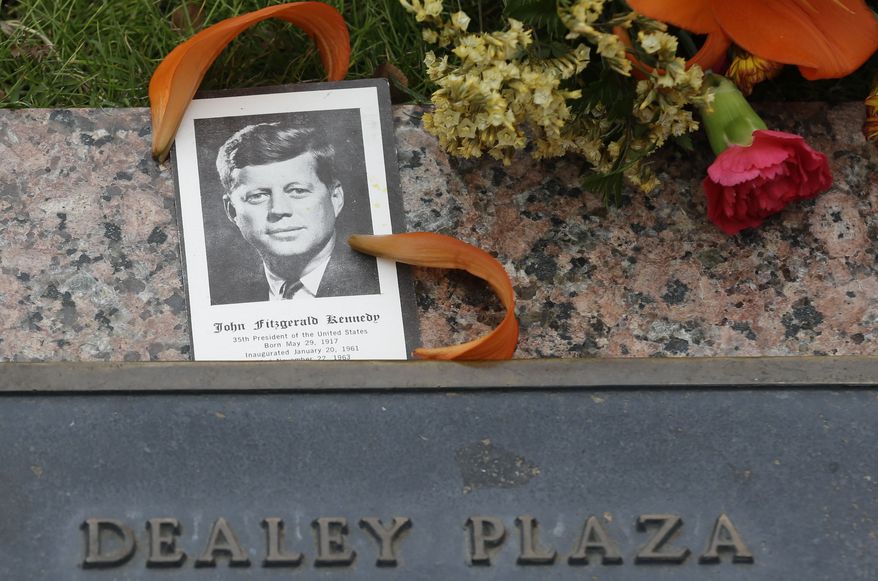 A photo of JKF and flowers lay on a plaque at Dealey Plaza in Dallas, Thursday, Nov. 21, 2013. Loose gatherings of the curious and conspiracy-minded at Dallas’ Dealey Plaza have marked past anniversaries of the assassination of President John F. Kennedy. But for the 50th anniversary, the city of Dallas has planned a solemn ceremony Friday in the plaza he was passing through when shots rang out. There will be brief remarks by the mayor and the tolling of church bells. (AP Photo/LM Otero)