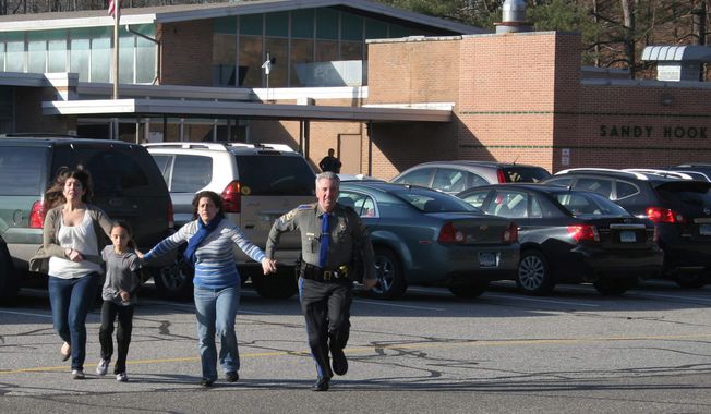 ** FILE ** A police officer leads two women and a child from Sandy Hook Elementary School in Newtown, Conn., where a gunman opened fire, killing 26 people, including 20 children, on Friday, Dec. 14, 2012. (AP Photo/Newtown Bee, Shannon Hicks)