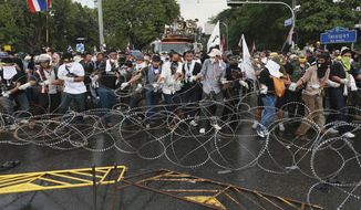 Anti-government protesters try to remove barbed wire set up by Thai riot police during a rally in Bangkok, Thailand, Monday, Nov. 25, 2013. Bangkok braced for major disruptions Monday as a massive anti-government march fanned out to 13 locations in a growing bid to topple the government of Prime Minister Yingluck Shinawatra. (AP Photo/Wason Wanitchakorn)