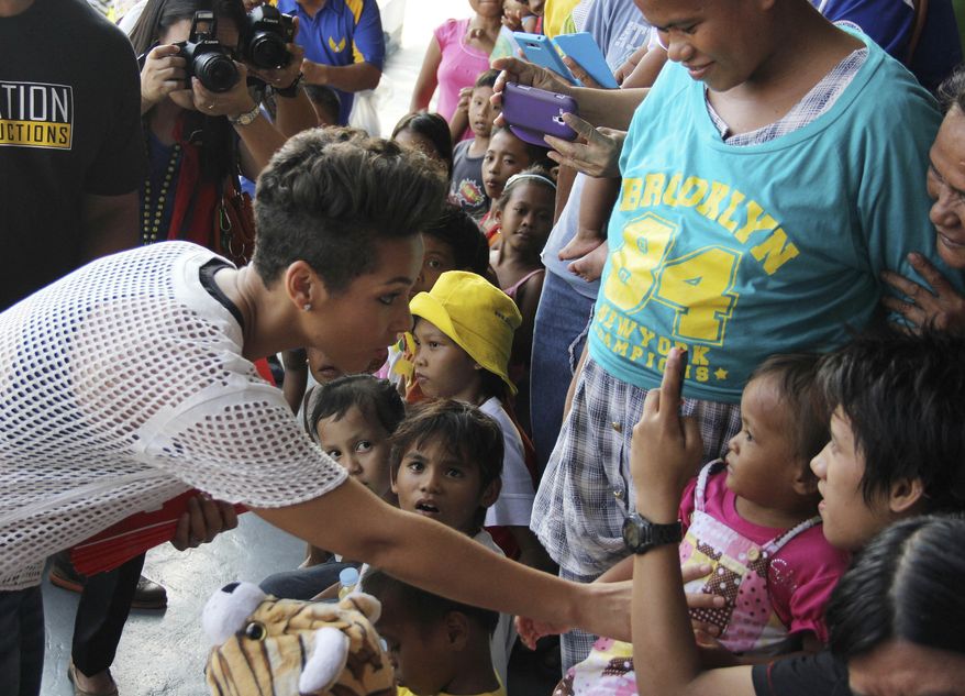 In this photo released by the Philippine Air Force, Grammy-winning singer Alicia Keys, left, touches a typhoon survivor as she visits the Villamor Air Base in suburban Pasay, south of Manila, Philippines, Monday Nov. 25, 2013. Keys visited the air force base to bring cheer to hundreds of evacuees from eastern Philippine provinces wracked by Typhoon Haiyan earlier this month. (AP Photo/Philippine Air Force)