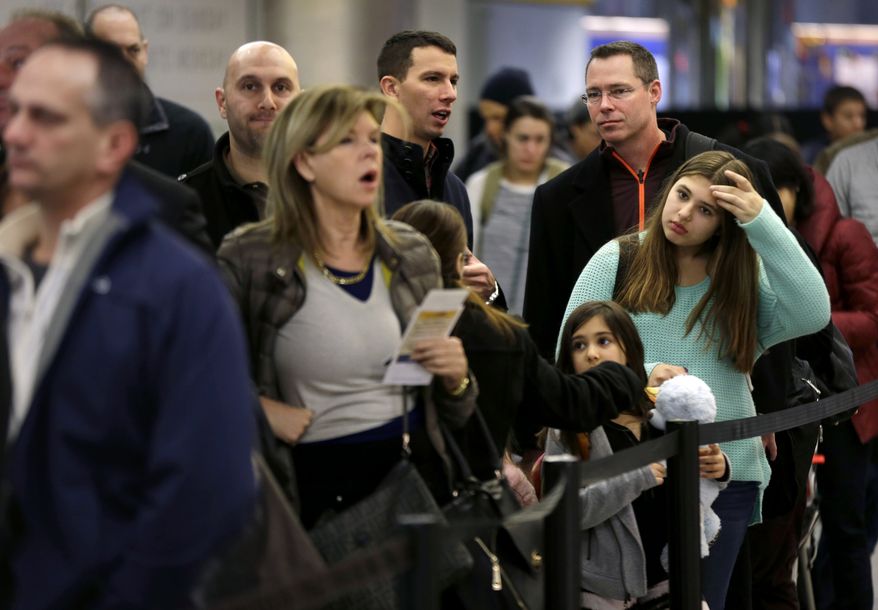 Travelers wait in line to board a flight at LaGuardia Airport in New York, Tuesday, Nov. 26, 2013. A winter storm system that hit parts of Arkansas, Oklahoma and Texas swept toward the densely populated East Coast on Tuesday, threatening to disrupt the plans of travelers ahead of the long Thanksgiving holiday weekend. (AP Photo/Seth Wenig)
