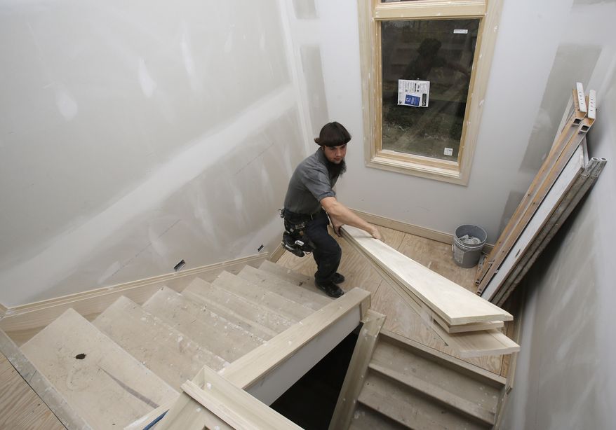 ** FILE ** In this Monday, Nov. 11, 2013, photo, Will Hostetler, a carpenter with Larry Block Builders, carries trim downstairs at a new home under construction, in Pepper Pike, Ohio. (AP Photo/Tony Dejak)