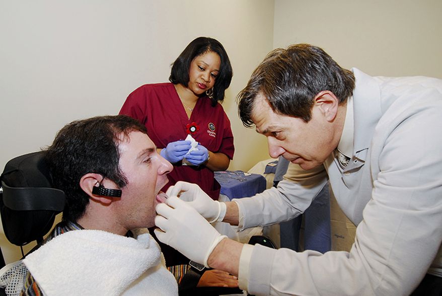 This undated handout photo provided by the Shepherd Center shows Jason DiSanto, left, receiving a tongue piercing at Georgia Tech in Atlanta. An experimental device is letting paralyzed people drive wheelchairs simply by flicking their tongue in the right direction. The Tongue Drive System was developed at Georgia Tech and tested at Shepherd Center in Atlanta. (AP Photo/Georgia Tech, Gary Meek)