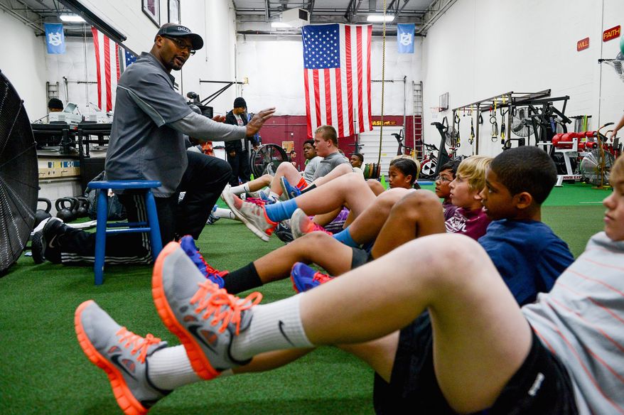 EARLY STUDY: Former Washington Redskins linebacker Eddie Mason works with young students at Mase Training in Sterling, Va. He advocates an approach that teaches the young the fundamentals of football without pads and full contact until they are in high school. (ANDREW HARNIK/THE WASHINGTON TIMES)