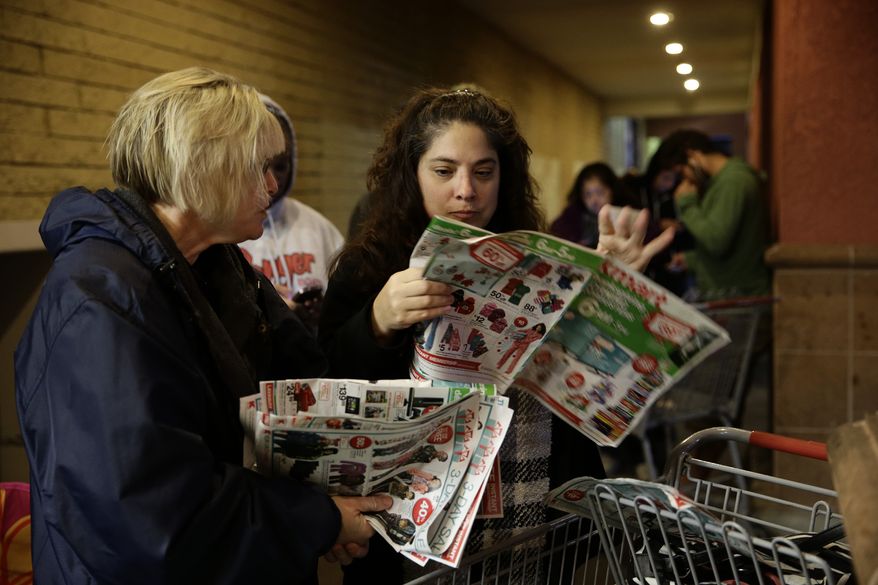 ** FILE ** Katie Stroh, left, and Gretchen Burkhardt look at catalogs while waiting outside a Kmart store on Thursday, Nov. 28, 2013, in Anaheim, Calif. Instead of waiting for Black Friday, which is typically the year's biggest shopping day, more than a dozen major retailers opened on Thanksgiving day this year. (AP Photo/Jae C. Hong)