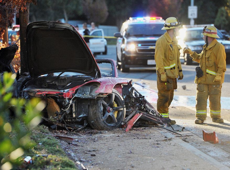 First responders gather evidence near the wreckage of a Porsche sports car that crashed into a light pole in Valencia, Calif., on Saturday, Nov. 30, 2013. "Fast & Furious" actor Paul Walker, 40, and another person were killed. (AP Photo/The Santa Clarita Valley Signal, Dan Watson)