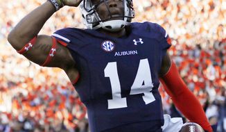 Auburn quarterback Nick Marshall (14) salutes after scoring against Alabama on a 45-yard touchdown run in the first half of an NCAA college football game in Auburn, Ala., Saturday, Nov. 30, 2013. (AP Photo/Dave Martin)