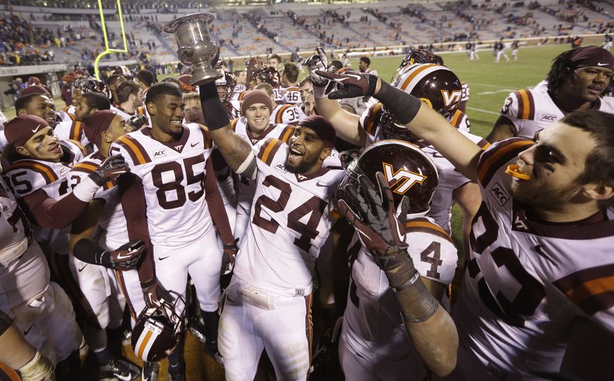 Virginia Tech linebacker Tariq Edwards (24) holds the Commonwealth Cup as he and his teammates celebrate their 16-6 win over Virginia after an NCAA college football game in Charlottesville, Va., Saturday, Nov. 30, 2013. (AP Photo/Steve Helber)