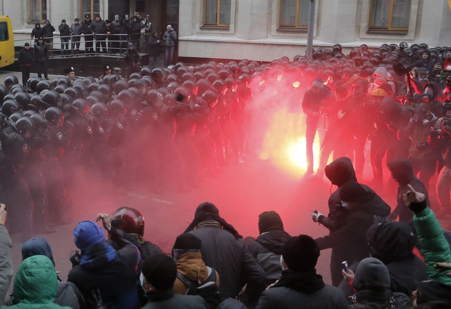 Protesters throw stones as they clash with riot police at the presidential office in Kiev on Sunday, Dec. 1, 2013. In the biggest show of anger yet over the Ukrainian president's refusal to sign an agreement with the European Union, as many as 100,000 demonstrators chased away police to rally in the center of the capital in defiance of a government ban on protests on Independence Square. (AP Photo/Efrem Lukatsky)
