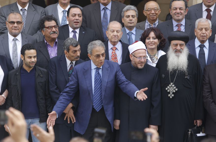 Amr Moussa (center), the chairman of Egypt's 50-member panel tasked with amending the nation's Islamist-drafted constitution, arranges the members for a group picture after finishing the final draft of a series of constitutional amendments at the Shoura Council in Cairo on Monday, Dec. 2, 2013. Adoption of the new charter will be a giant step in the implementation of the road map announced by the nation's military chief when he toppled President Mohammed Morsi in a July 3 coup. The next steps will be parliamentary and presidential elections in the spring and summer of 2014. (AP Photo/Amr Nabil)