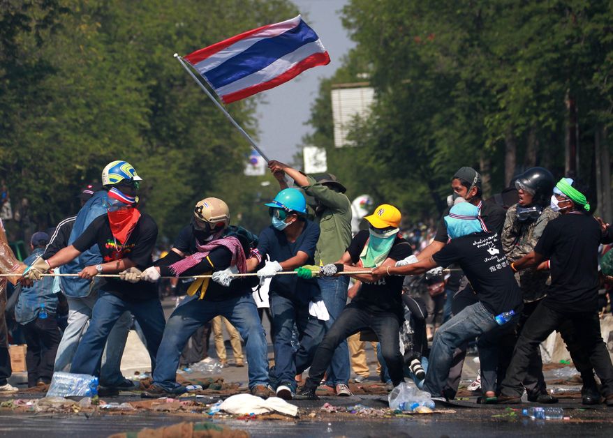 Anti-government protesters pull rope to remove police barricade near the Government House in Bangkok, Monday, Dec. 2, 2013. Thailand's Prime Minister Yingluck Shinawatra said Monday she is willing to do anything it takes to end violent protests against her government and restore peace, but cannot accept the opposition's "unconstitutional" demand to hand power to an unelected council. (AP Photo/Wason Wanichakorn)