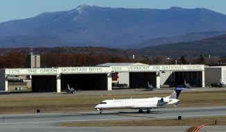 A commercial jetliner taxis past Vermont Air National Guard F-16 fighter jets sitting outside a hangar at Burlington International Airport in South Burlington, Vt., on Monday, Nov. 4, 2013. (AP Photo/Toby Talbot)