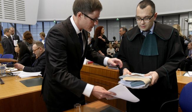 Michael Pietrzak (right), one of the attorneys for Abd al-Rahim al-Nashiri and Abu Zubaydah, is helped by an unidentified assistant as he arrives at the European Court of Human Rights in Strasbourg, France, on Tuesday, Dec. 3, 2013. Lawyers for two terror suspects, currently held by the U.S. in Guantanamo Bay, Cuba, accuse Poland of human rights abuses. (AP Photo/Christian Lutz)
