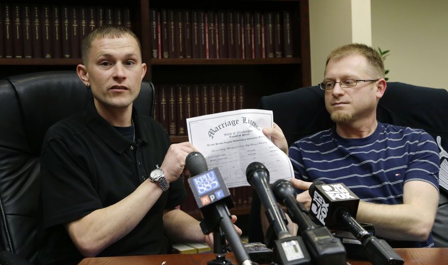 Michael (left) and Eli Hall hold their marriage license certificate on Tuesday, Dec. 3, 2013, as they talk to reporters in Seattle. Michael Hall, a locomotive engineer for BNSF Railway Co., is suing the company for repeatedly denying husband Eli spousal health benefits even though gay marriage is legal in Washington state. (AP Photo/Ted S. Warren)