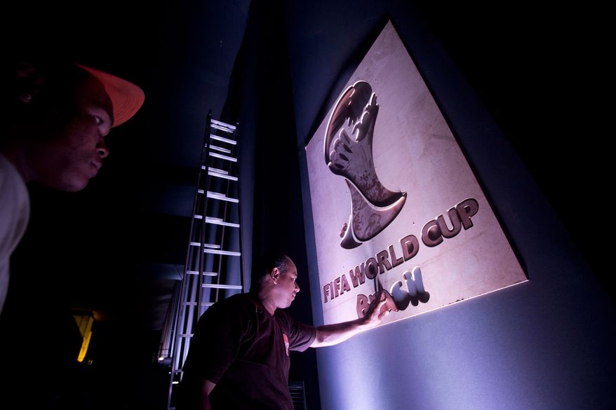 A worker puts the finishing touches to a sign at the entrance for the 2014 soccer World Cup draw in Costa do Sauipe, Brazil, Thursday, Dec. 5, 2013. The draw for the 2014 World Cup finals takes place Friday, Dec. 6. (AP Photo/Victor R. Caivano)